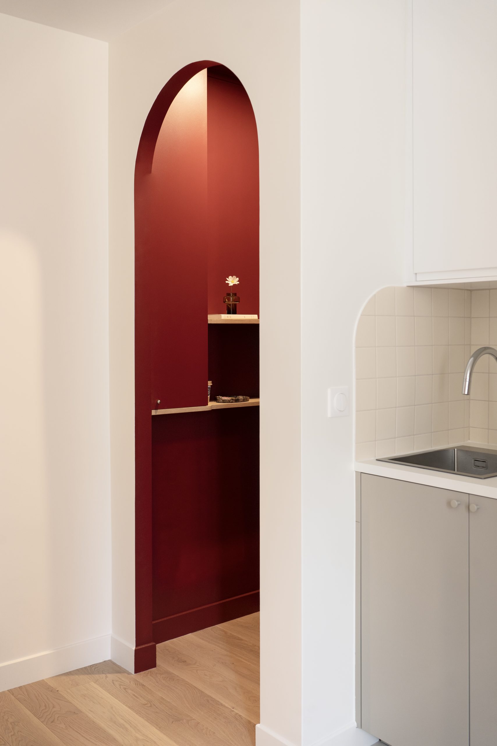 Niche murale arquée rouge intégrée dans un appartement rénové au style contemporain