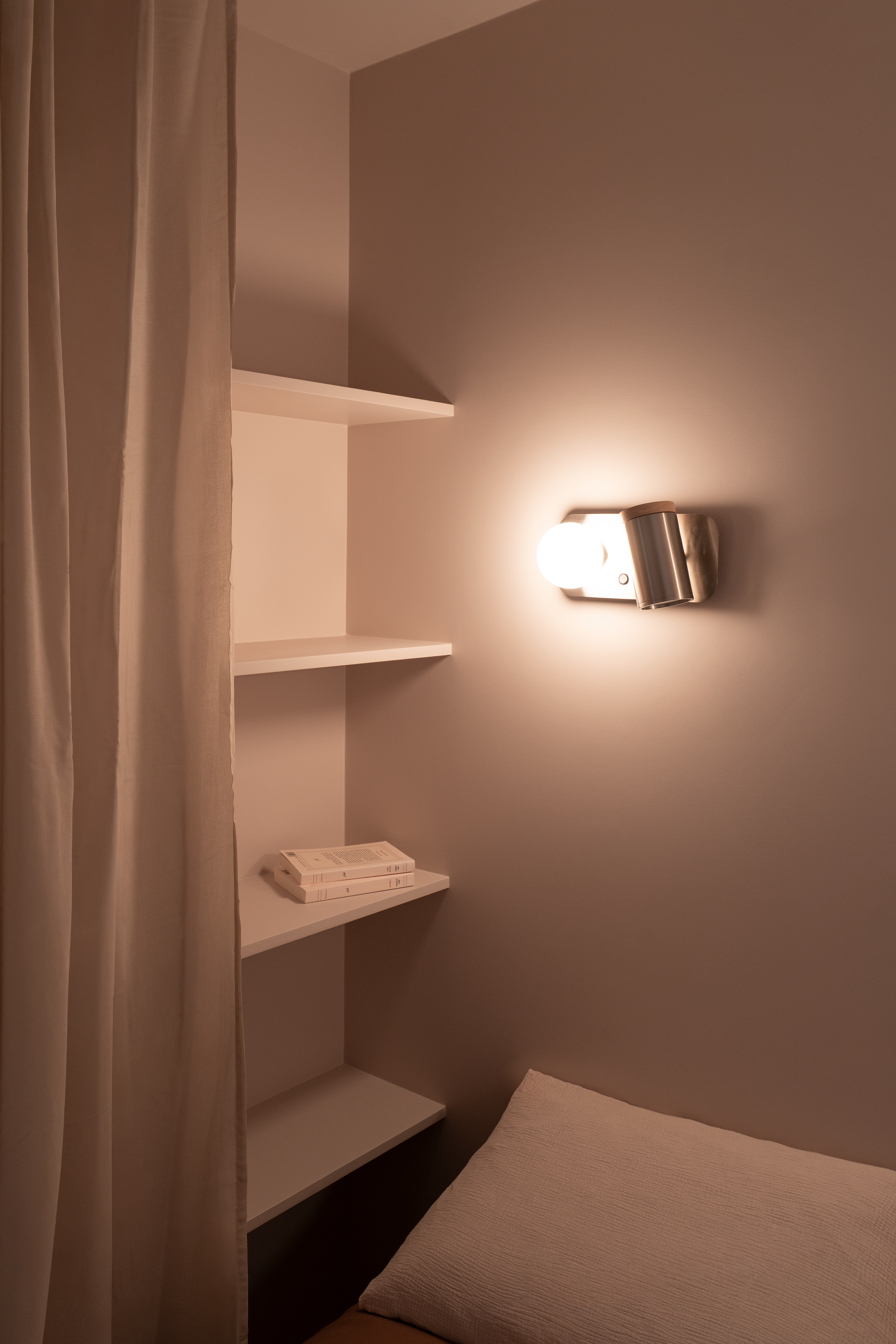 Placards sur mesure blancs avec niches ouvertes et arche menant au coin nuit dans un studio bien agencé