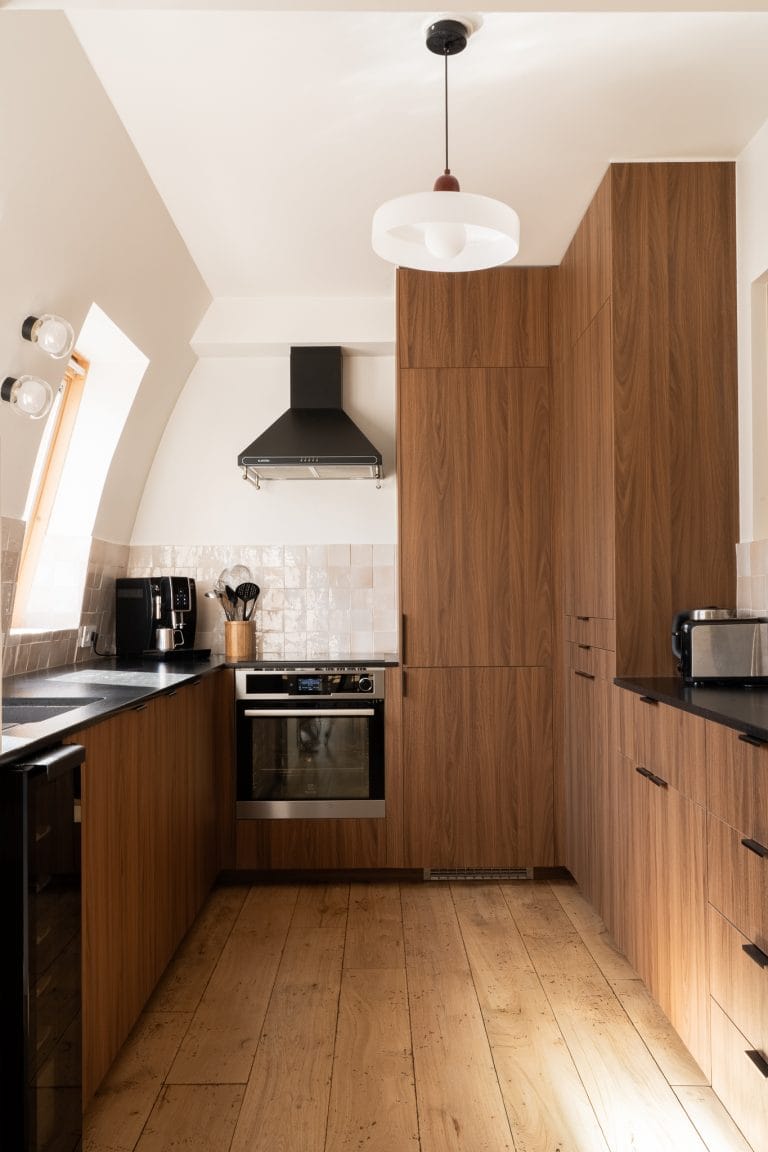 Cuisine équipée en placages bois noyer avec plan de travail noir, hotte et four intégrés