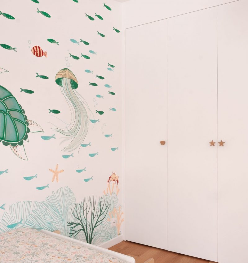 Chambre d’enfant avec fresque murale marine et rangements intégrés en blanc.