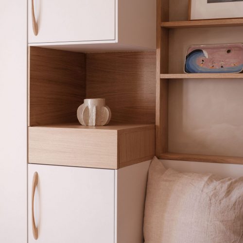 Zoom sur un coin cosy avec coussins et détails de rangement en bois