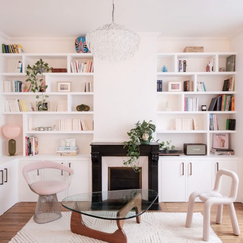 Bibliothèque sur mesure blanche avec rangements bas et cheminée noire dans un appartement haussmannien