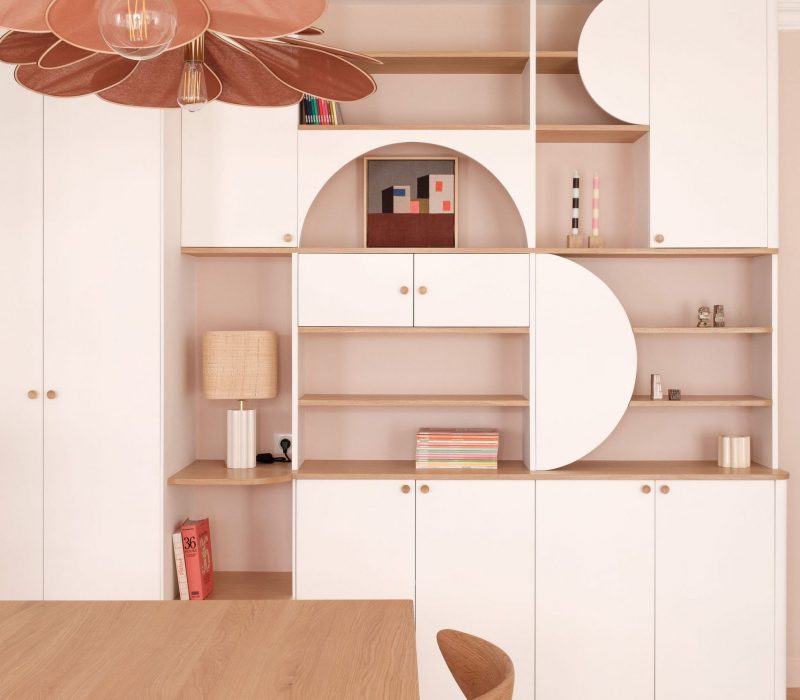 Bibliothèque sur-mesure en bois et blanc avec des courbes arrondies et des niches décoratives.