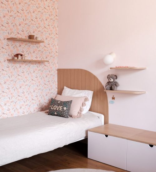 Camille_Huguenot_LesDecoreuses_Fondary_HD-1 Chambre enfant avec mur en papier peint floral, mobilier arrondi et rangements bas.