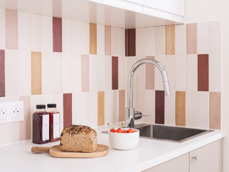 Cuisine minimaliste avec plan de travail blanc et carrelage mural rose et ocre