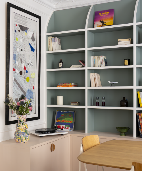 Bibliothèque intégrée vert sauge avec objets décoratifs et meuble bas sur mesure dans un intérieur haussmannien