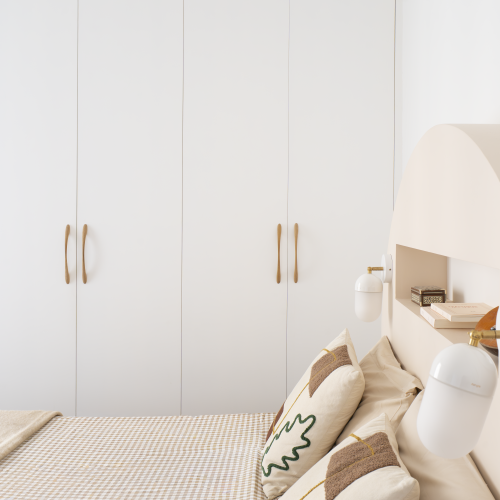 Chambre avec rangements sur mesure blancs, tête de lit arrondie et linge de lit beige