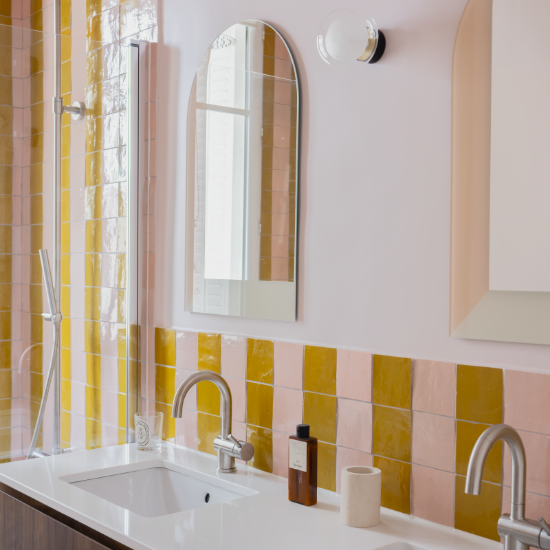 Salle de bain avec double vasque, meuble en bois foncé et carrelage rose et ocre