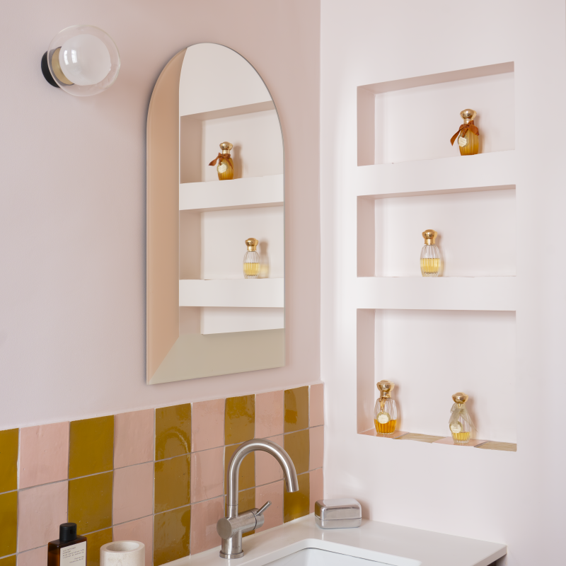 Détail de salle de bain avec miroir arrondi, niches murales et robinetterie moderne