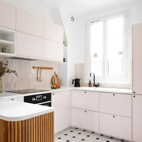 Cuisine rénovée avec meubles rose pastel et comptoir arrondi en tasseaux de bois