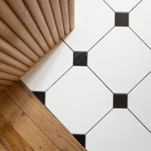 Détail du sol en carrelage noir et blanc contrastant avec les meubles pastel