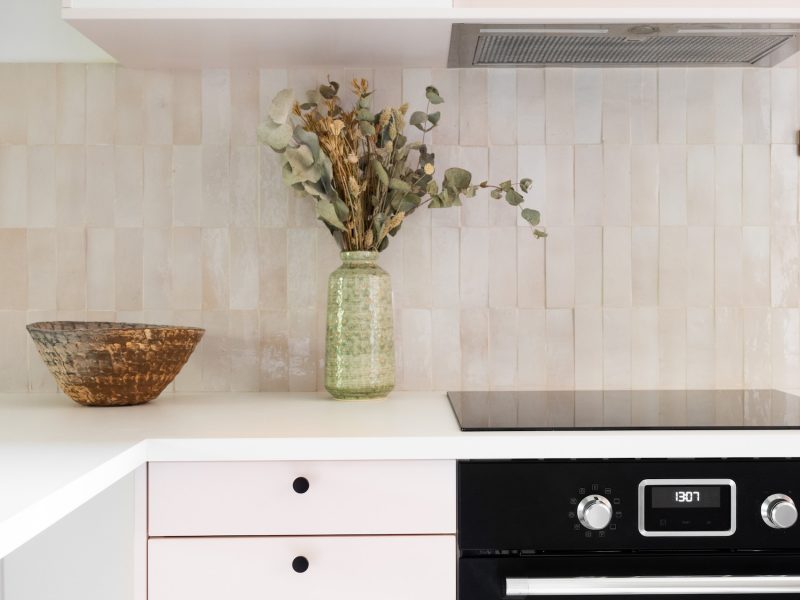 Cuisine rénovée avec meubles rose pastel et comptoir arrondi en tasseaux de bois