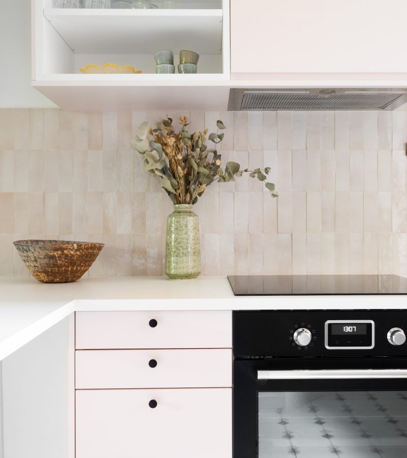 Cuisine rénovée avec meubles rose pastel et comptoir arrondi en tasseaux de bois