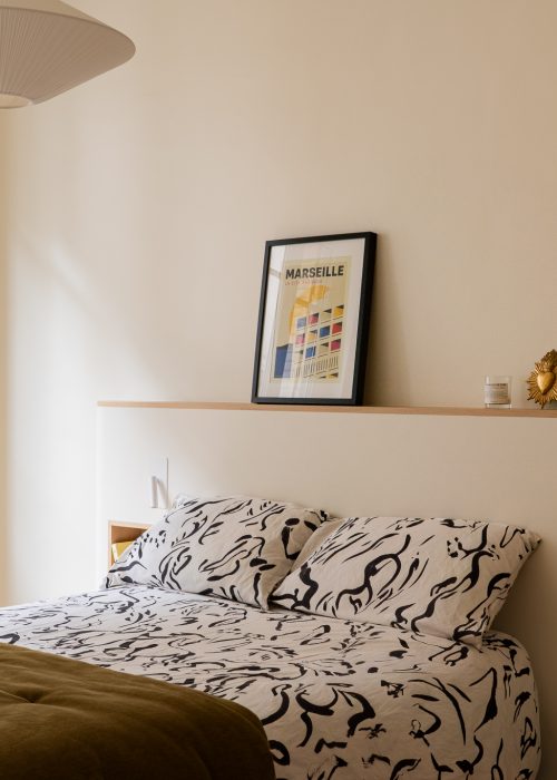 Chambre lumineuse avec tête de lit sur mesure, tablette en chêne et affiche Marseille Cité Radieuse