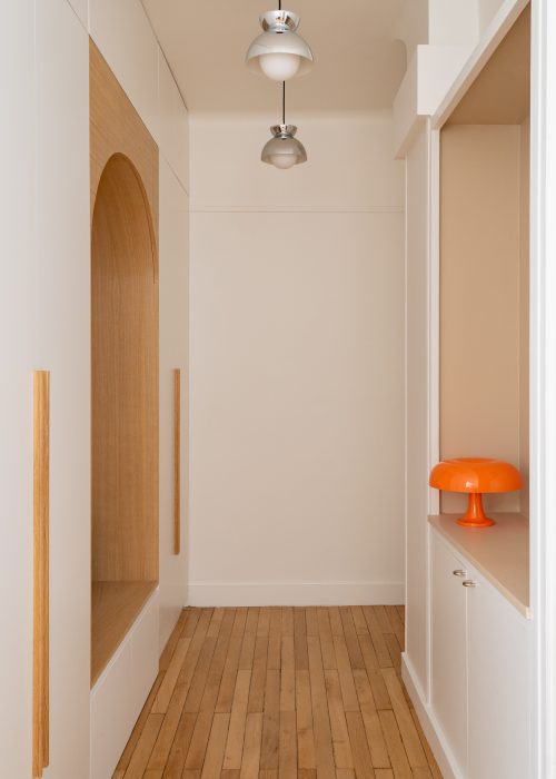 Niche d'entrée avec lampe champignon orange Nesso et affiche encadrée sur mur terracotta