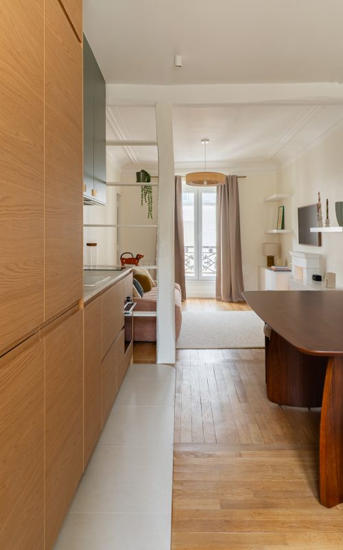 Cuisine couloir en chêne avec vue sur le séjour, poutre apparente et parquet ancien