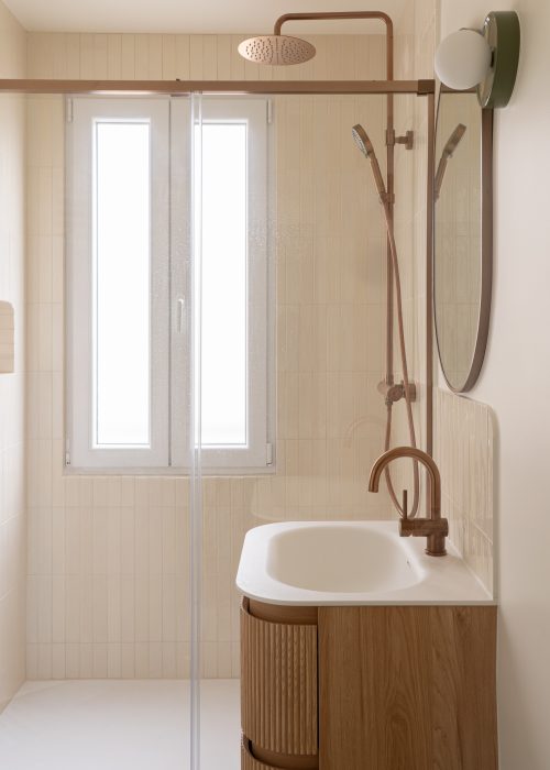 Salle de bains avec douche, vasque chêne, robinetterie cuivre et zellige crème