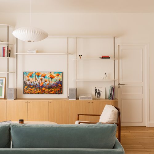 Séjour lumineux avec étagères murales, TV cadre, enfilade en chêne et suspension Nelson Bubble